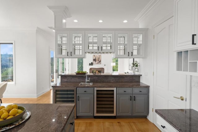 bar featuring white cabinetry, gray cabinetry, beverage cooler, and dark stone counters