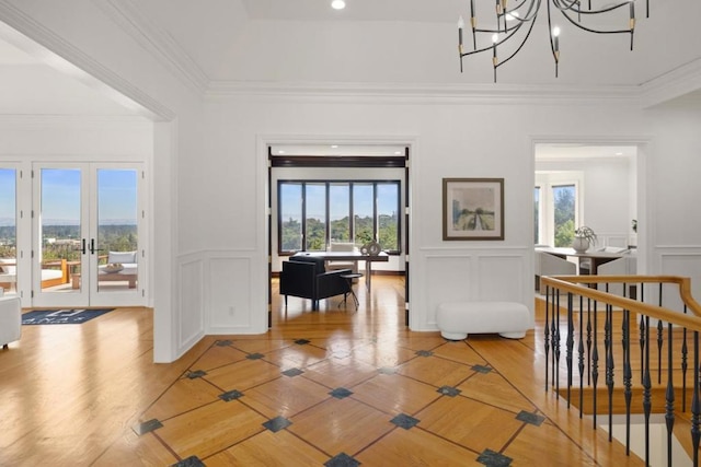 interior space with crown molding, wood-type flooring, a chandelier, and french doors