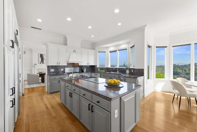 kitchen featuring a center island, gray cabinets, custom range hood, decorative backsplash, and white cabinets