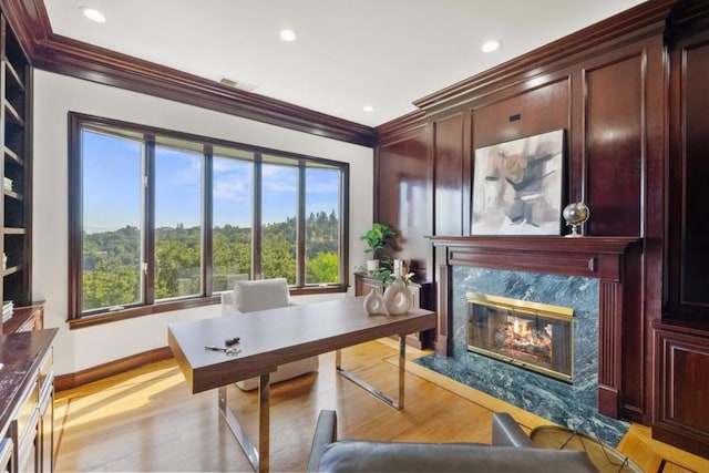 office featuring light hardwood / wood-style flooring, a high end fireplace, and ornamental molding