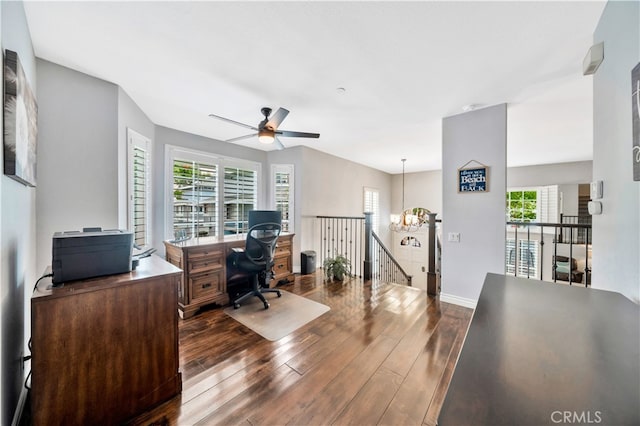 office space featuring ceiling fan with notable chandelier, dark hardwood / wood-style flooring, and a healthy amount of sunlight