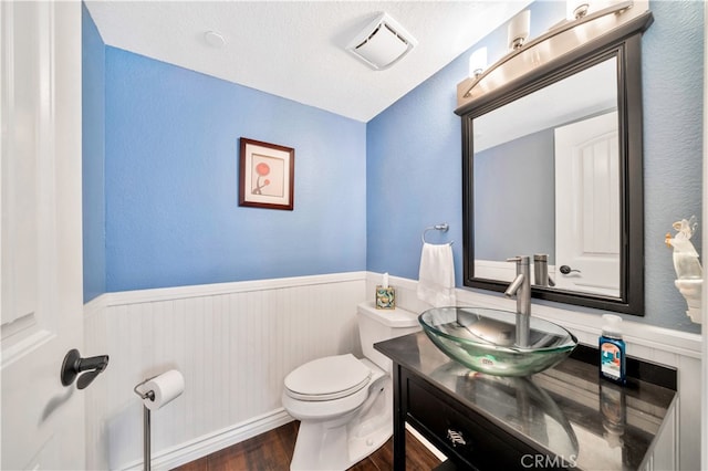 bathroom featuring a textured ceiling, hardwood / wood-style floors, vanity, and toilet