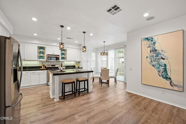 kitchen featuring a center island, light wood-type flooring, white cabinetry, and appliances with stainless steel finishes