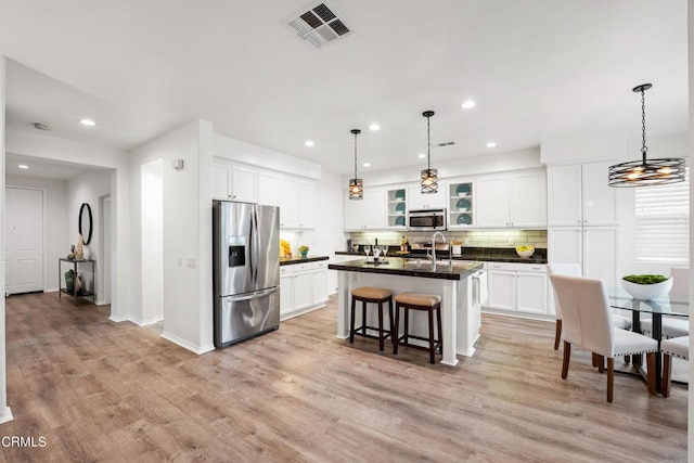 kitchen featuring white cabinetry, a center island with sink, light hardwood / wood-style flooring, and appliances with stainless steel finishes