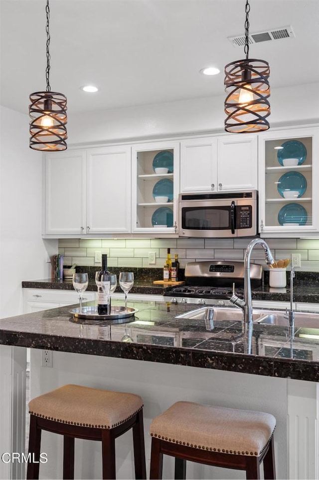 kitchen featuring white cabinetry, decorative light fixtures, and appliances with stainless steel finishes