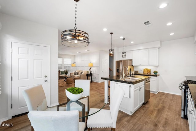 kitchen with white cabinetry, a kitchen island with sink, pendant lighting, and appliances with stainless steel finishes