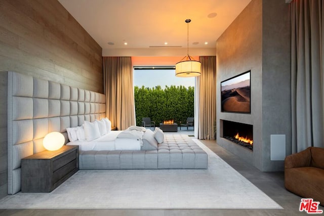 bedroom with concrete floors, a large fireplace, and access to exterior