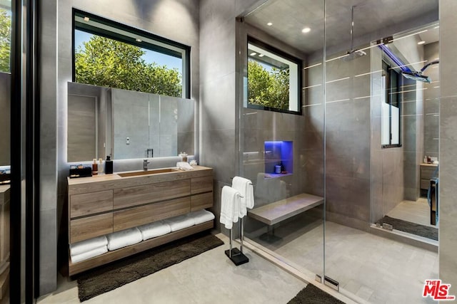 bathroom with tile walls, vanity, and walk in shower