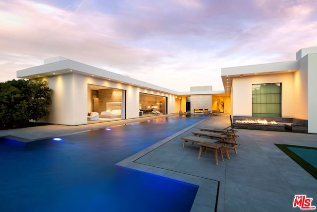 pool at dusk featuring a patio area