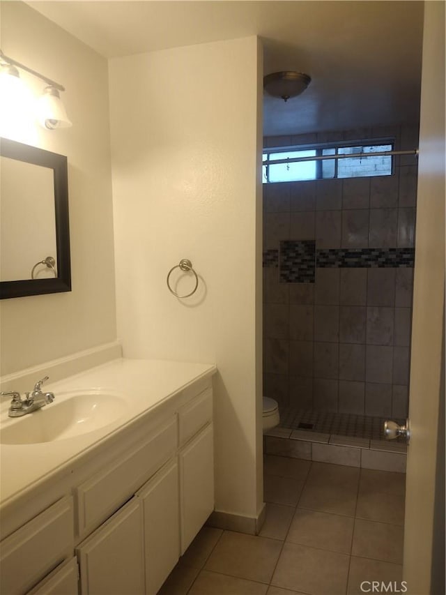 bathroom featuring tile patterned flooring, vanity, toilet, and a tile shower