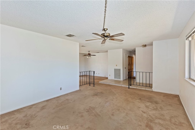 carpeted spare room featuring ceiling fan and a textured ceiling