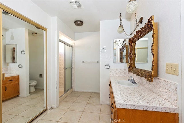 bathroom featuring vanity, toilet, a shower with door, and tile patterned floors