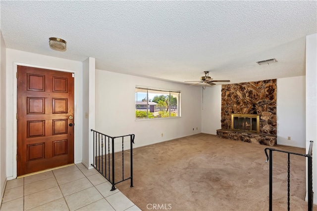 carpeted living room featuring a fireplace, ceiling fan, and a textured ceiling