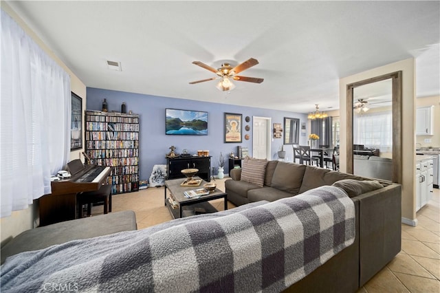 tiled living room with ceiling fan with notable chandelier