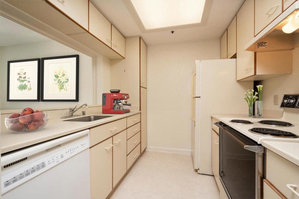 kitchen featuring white appliances, sink, and cream cabinetry