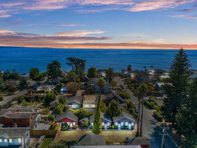 aerial view at dusk featuring a water view