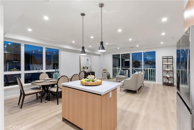 kitchen featuring pendant lighting, stainless steel refrigerator with ice dispenser, light hardwood / wood-style flooring, light brown cabinetry, and a kitchen island