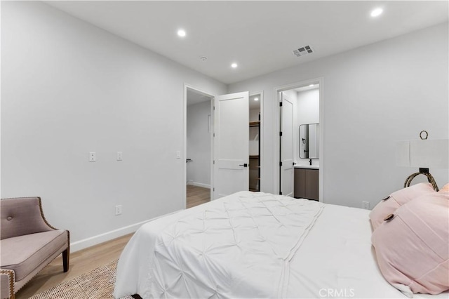 bedroom with connected bathroom and light wood-type flooring