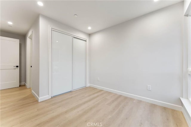 unfurnished bedroom featuring light hardwood / wood-style flooring and a closet