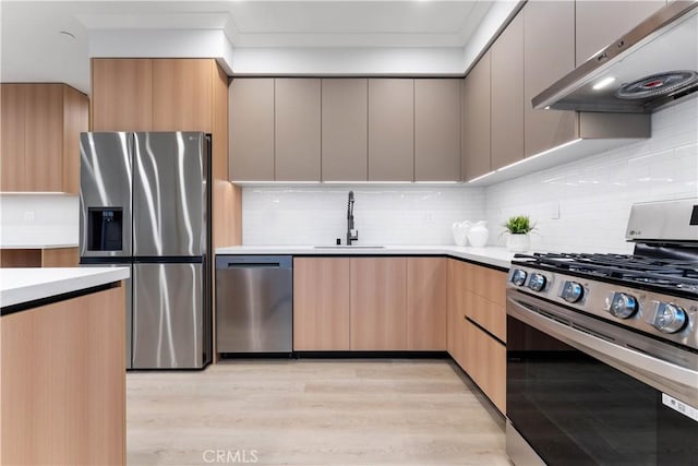 kitchen featuring appliances with stainless steel finishes, extractor fan, sink, light brown cabinets, and light hardwood / wood-style flooring