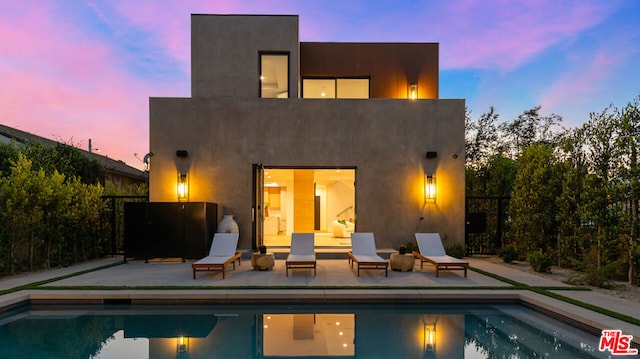 back house at dusk featuring a patio area