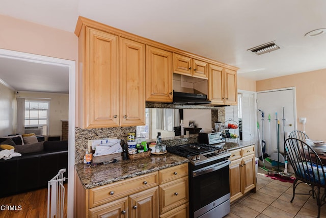 kitchen with gas stove, dark stone countertops, decorative backsplash, cooling unit, and light tile patterned floors