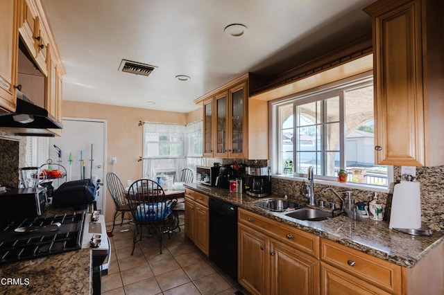 kitchen with light tile patterned floors, dishwasher, dark stone counters, and sink