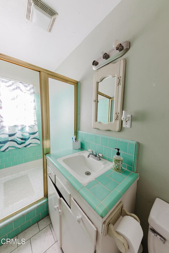 bathroom with tile patterned flooring, a shower, vanity, and toilet