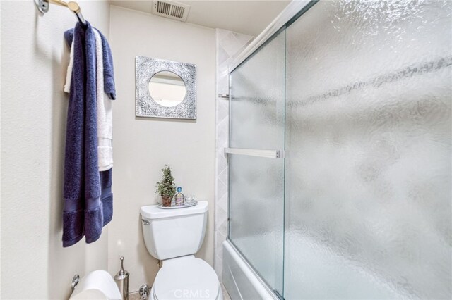 bathroom with combined bath / shower with glass door and toilet