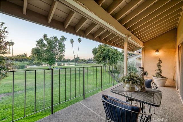 patio terrace at dusk with a water view and a lawn