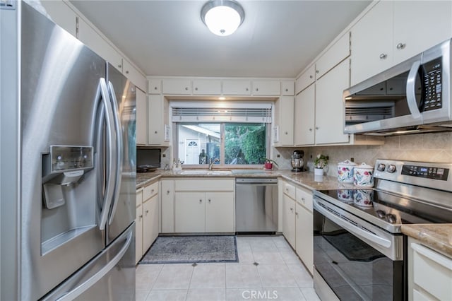 kitchen featuring stainless steel appliances, tasteful backsplash, sink, light tile patterned flooring, and white cabinetry