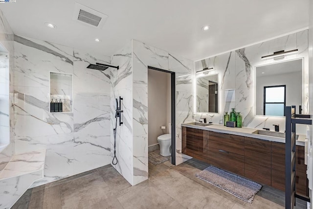 bathroom featuring tile walls, tiled shower, vanity, and toilet