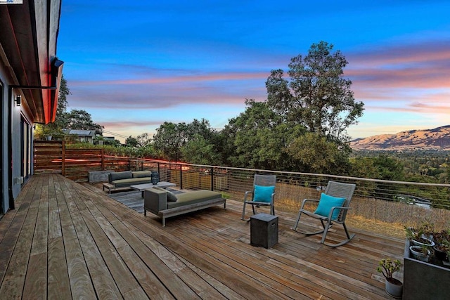 deck at dusk with an outdoor living space and a mountain view