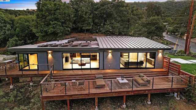 back house at dusk featuring a wooden deck