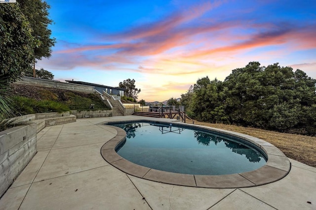 pool at dusk with a patio area