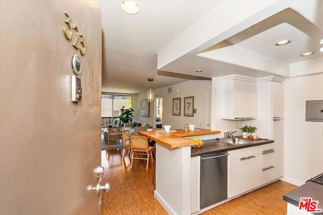 kitchen with wood counters, sink, stainless steel dishwasher, decorative light fixtures, and white cabinetry