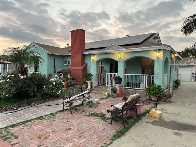 view of front facade with solar panels, covered porch, and a garage