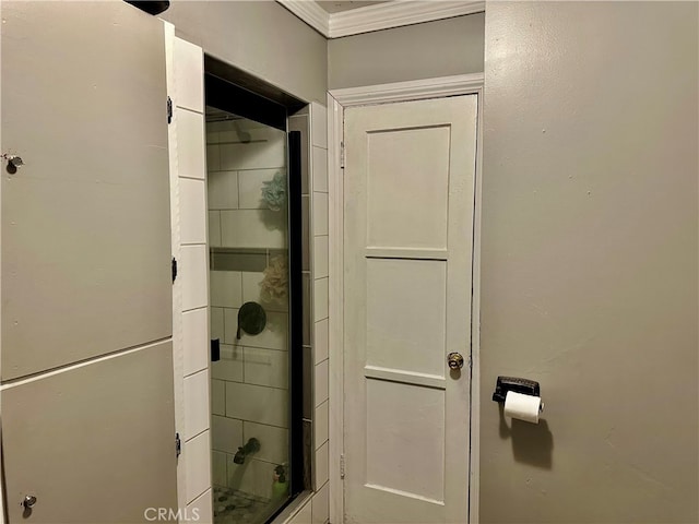 bathroom with a shower with door and crown molding