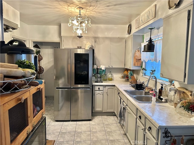 kitchen featuring sink, stainless steel fridge, pendant lighting, light tile patterned floors, and a chandelier