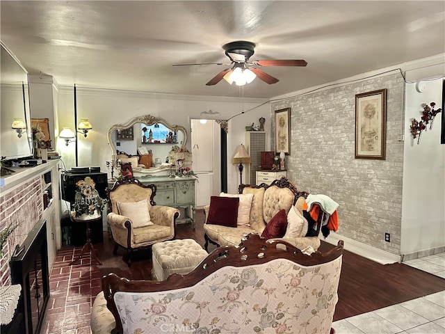 living room with ceiling fan, crown molding, light wood-type flooring, and a fireplace