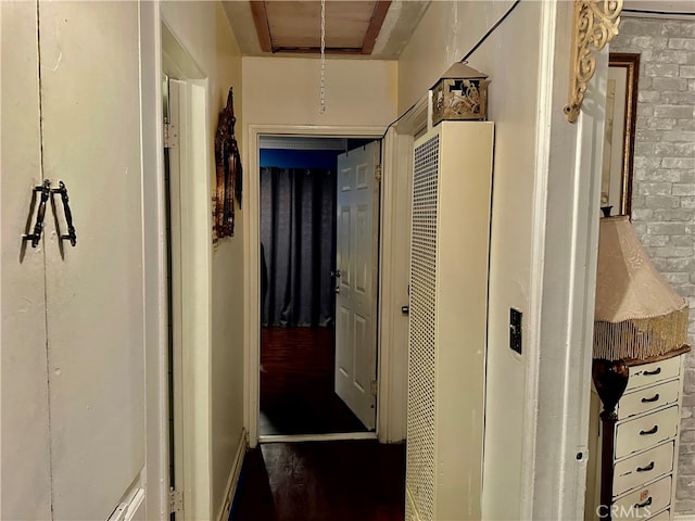 hallway with brick wall and hardwood / wood-style floors