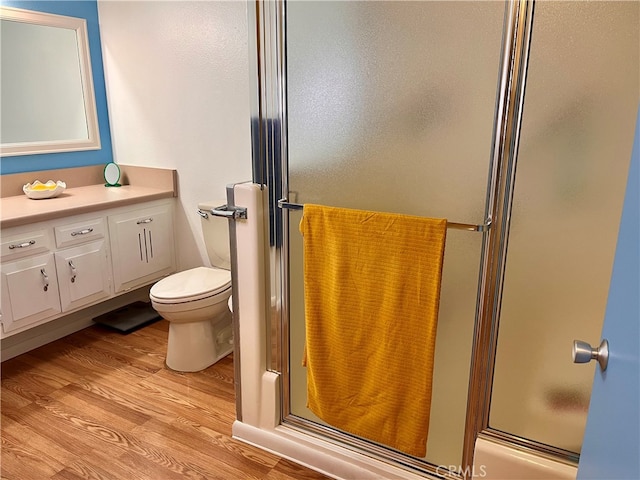 bathroom with walk in shower, vanity, hardwood / wood-style floors, and toilet