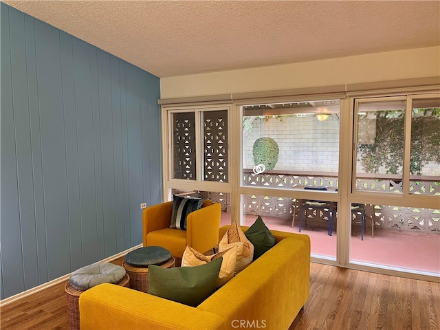 sitting room featuring wooden walls, hardwood / wood-style floors, and a textured ceiling