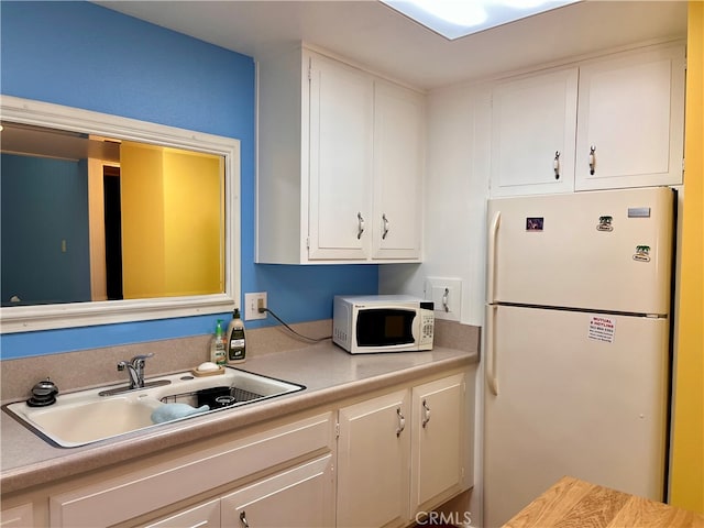 kitchen with white appliances, sink, and white cabinetry