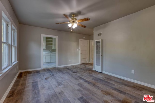 unfurnished bedroom with wood-type flooring, connected bathroom, and ceiling fan