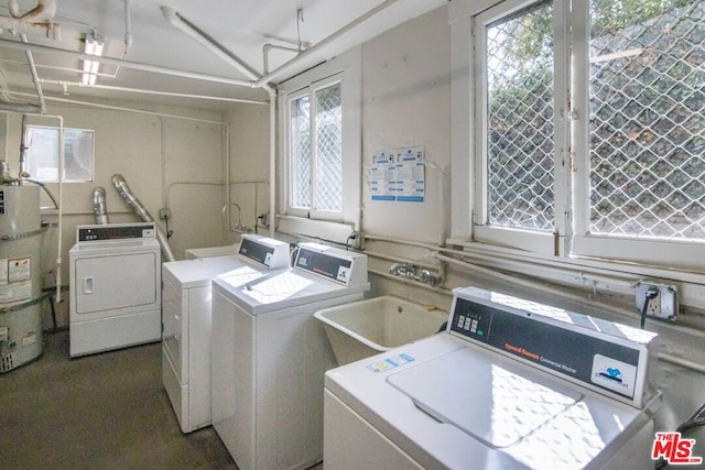 washroom with a healthy amount of sunlight, strapped water heater, washer and clothes dryer, and sink