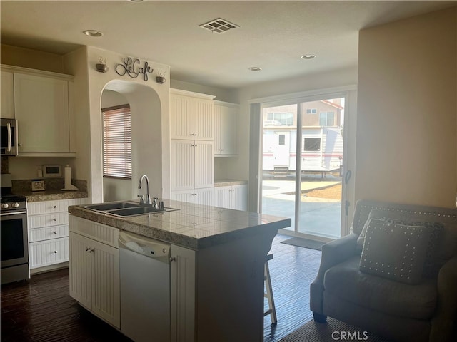 kitchen featuring sink, a kitchen island with sink, white cabinetry, stainless steel appliances, and dark hardwood / wood-style floors