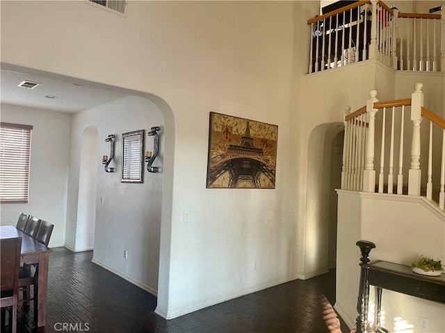 corridor featuring a towering ceiling and dark hardwood / wood-style flooring