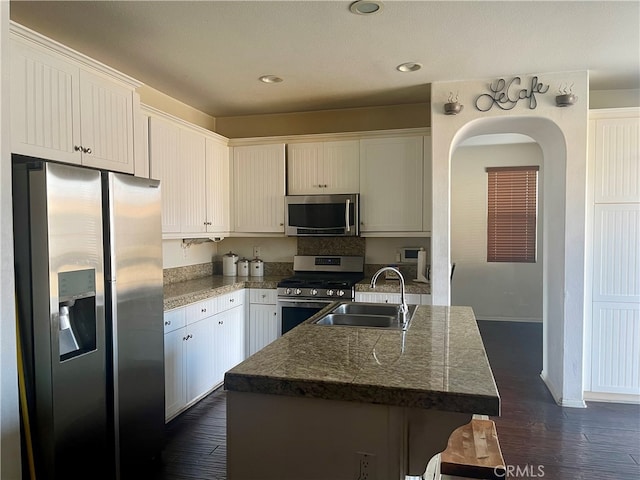 kitchen with white cabinets, an island with sink, sink, stainless steel appliances, and dark hardwood / wood-style floors