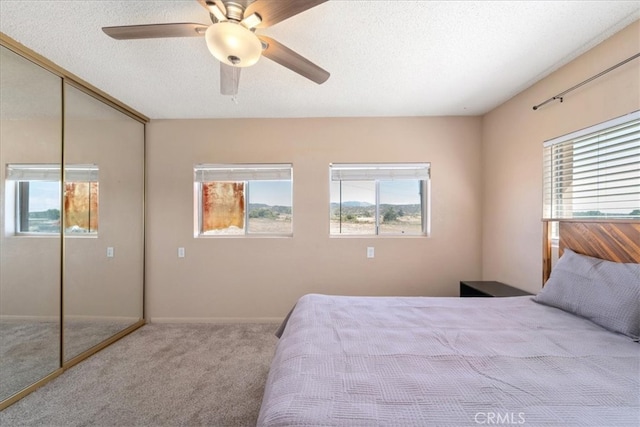 bedroom with a textured ceiling, a closet, multiple windows, and ceiling fan